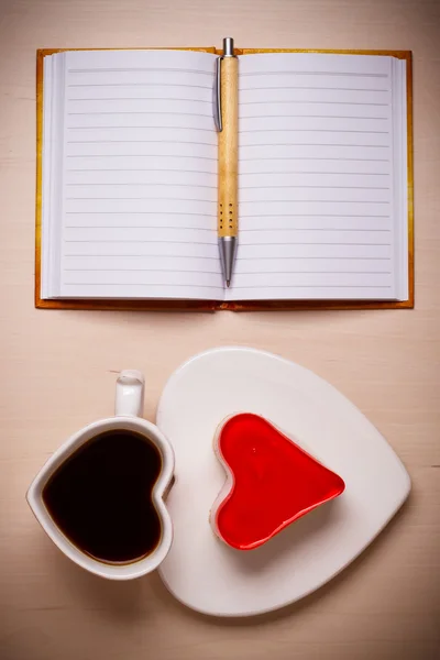 Coffee cup cake in heart form and notebook