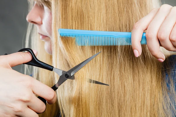 Girl is cutting her hair down.