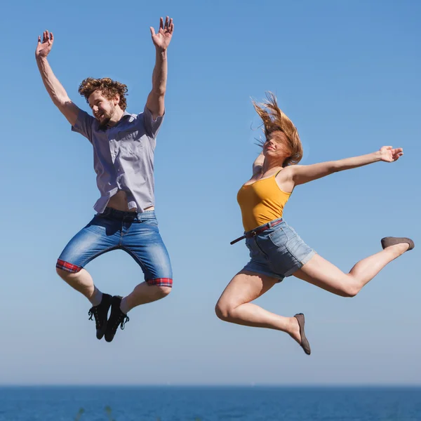 Carefree couple jumping by sea ocean water.