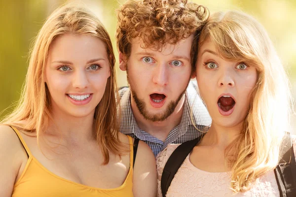Three surprised young people friends outdoor.