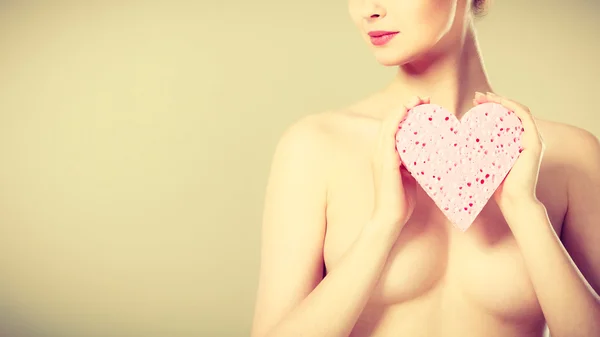 Naked woman holding heart shaped sponge