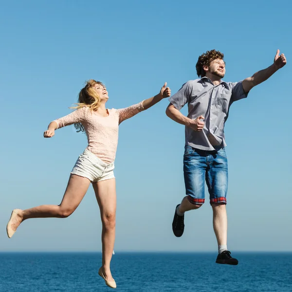 Carefree couple jumping by sea ocean water.
