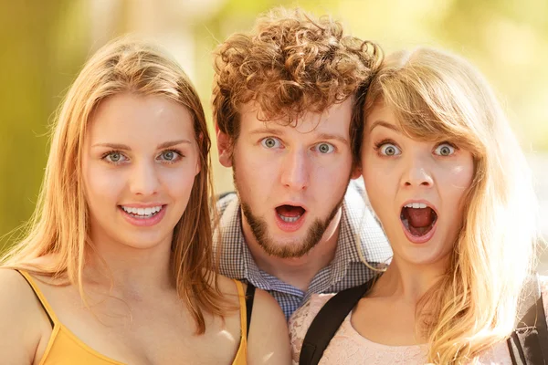 Three surprised young people friends outdoor.