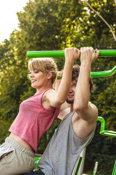 Man and woman exercising on pulldown outdoor.