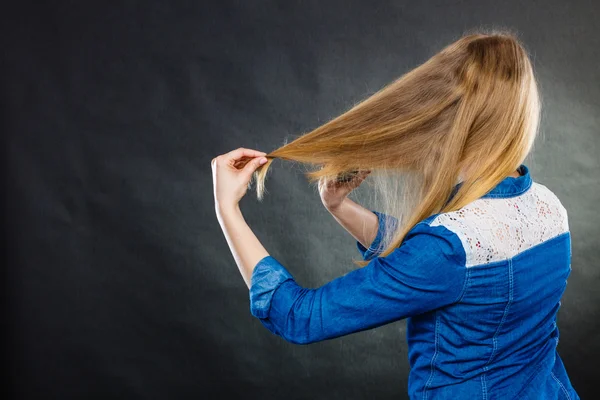 Blonde woman combing her hair.