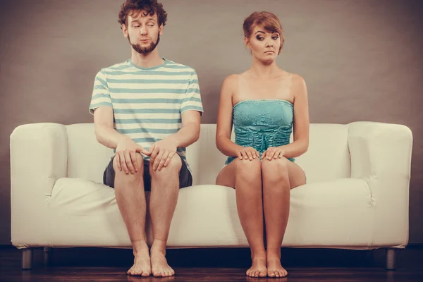 Shy woman and man sitting on couch