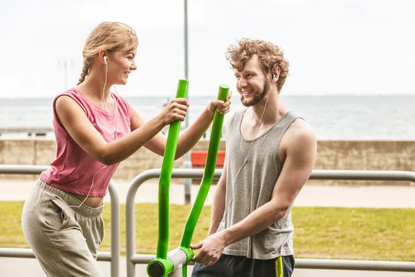 Man and woman exercising on elliptical trainer.