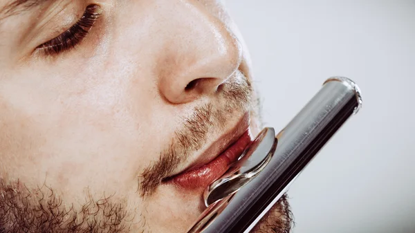 Male flutist playing his flute closeup