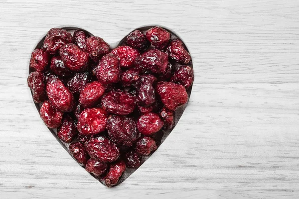 Dried cranberry fruit heart shaped on wood board