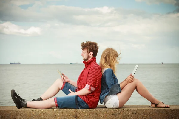 Woman with smartphone man with tablet couple outdoor