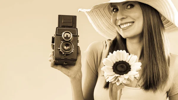 Woman holding sunflower and old camera