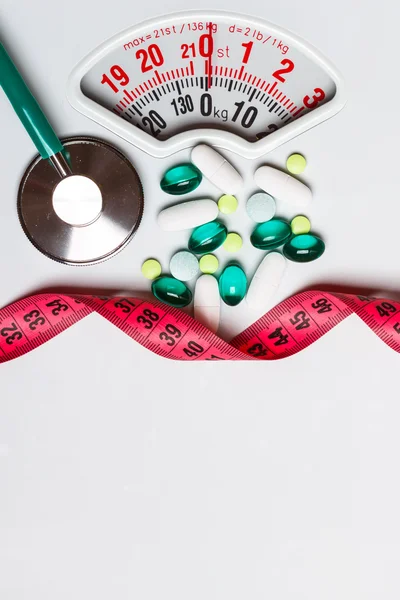 Pills stethoscope measuring tape on scales. Health care