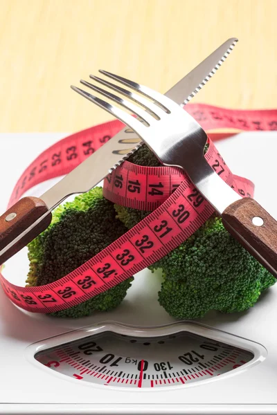Broccoli with measuring tape on weight scale. Dieting