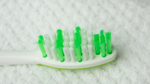 Green brush toothbrush in bathroom on towel