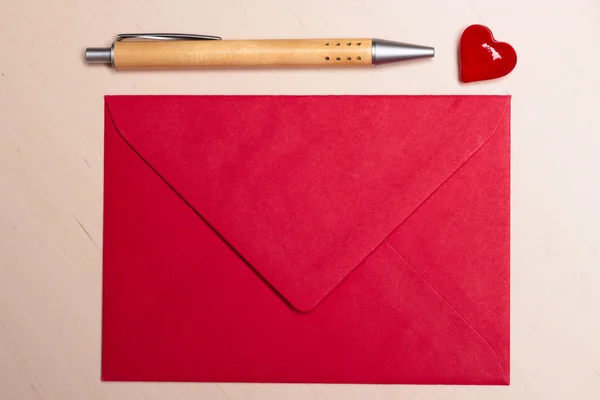 Red envelope heart and pen on table