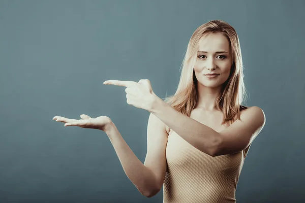 Young woman holding open palm showing copy space