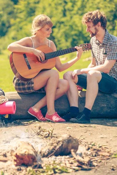 Young couple camping playing guitar outdoor