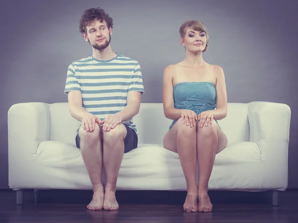 Shy woman and man sitting close to each other on couch.