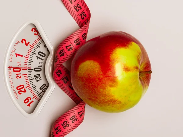 Apple with measuring tape on weight scale. Dieting