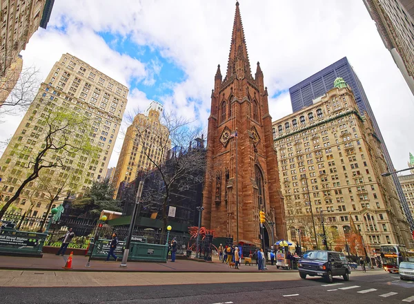Street with tourists and traffic and Trinity Church in Manhattan