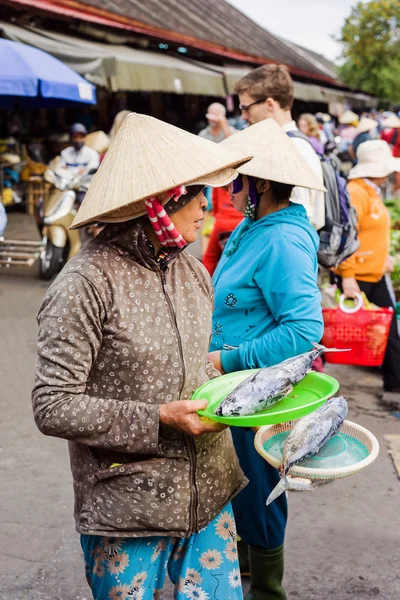 Asian woman selling fresh fish in street market in Vietnam
