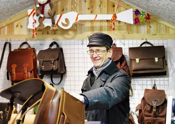Smilling man offering handmade leather bags at Vilnius Christmas market