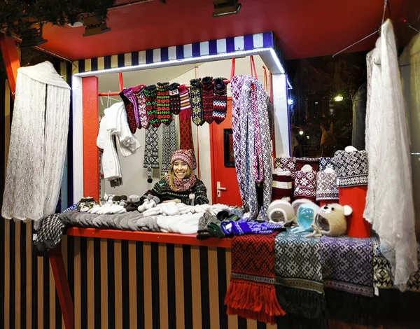 Smiling woman sells warm clothes at the Riga Christmas Market