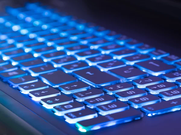 Pc keyboard with blue light tint, close-up view