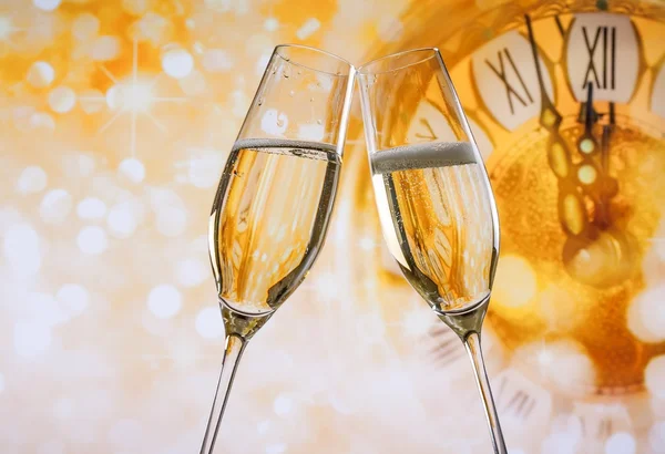 New Year or Christmas at midnight with champagne flutes make cheers, golden bokeh and clock