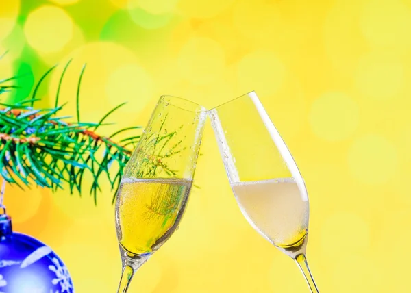 Champagne flutes with golden bubbles on christmas decoration yellow bokeh background
