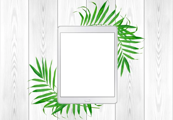 Tablet pc in green fern leaves frame on white wood table. Top Vi