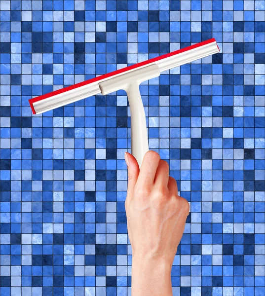Woman hand with special squeegee for cleaning over blue tile bac
