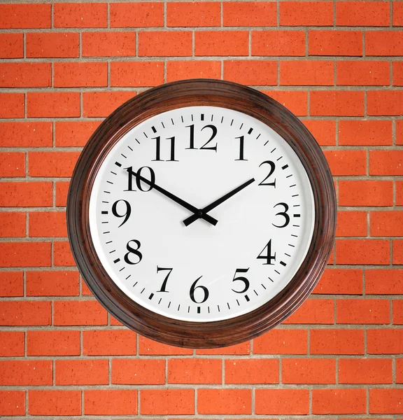 Wall clock with wooden frame over orange brick wall