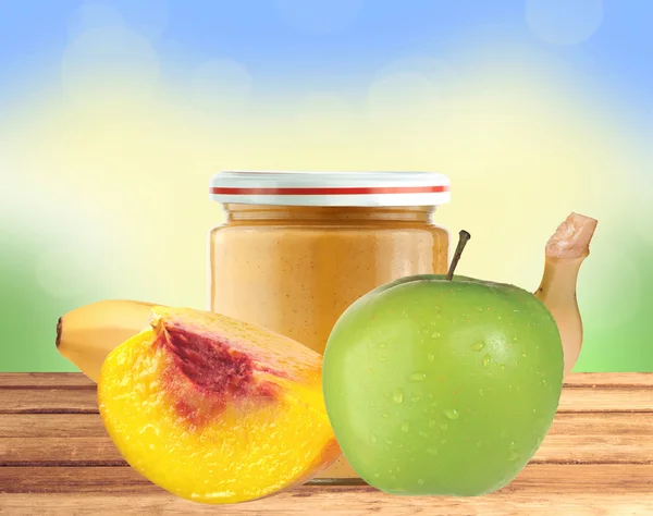 Jar of baby puree, peach, apple and banana on wooden table over