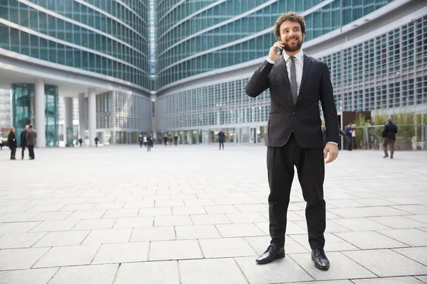 Businessman talking to mobile outside office building