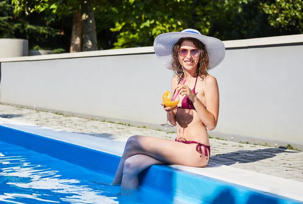 Happy smiling woman with straw hat in swimming pool