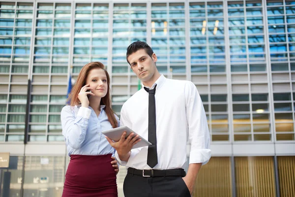 Business people working outside office building with digital devices