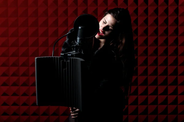 Young beautiful singer singing in a studio recording