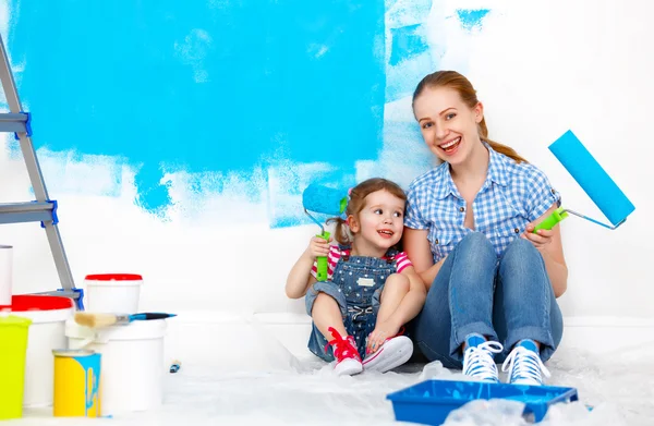 Happy family mother and child daughter making repairs, paint wal