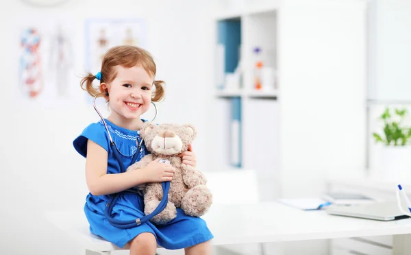 Child girl playing doctor with teddy bear