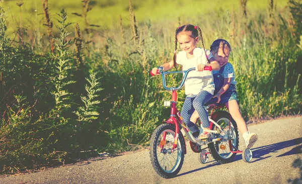 Happy children sister  girl cyclist riding a bike