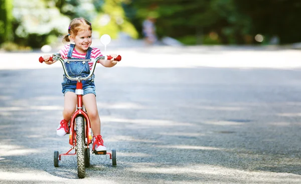 Happy child girl cyclist riding a bike