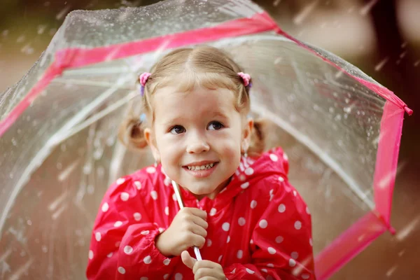 Happy child girl laughing with an umbrella in rain