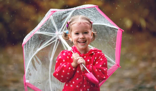 Happy child girl laughing with an umbrella in rain