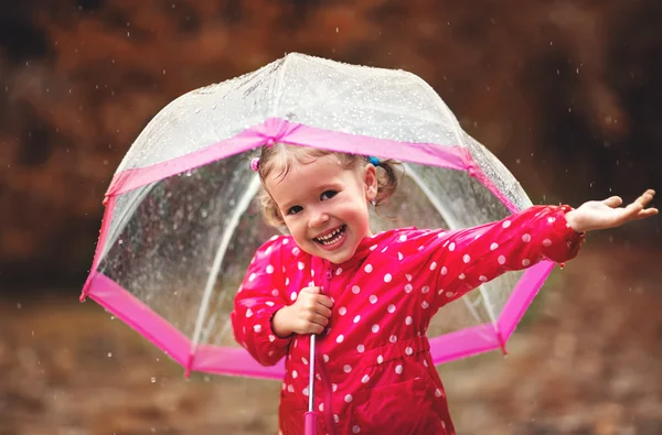 Happy child girl laughing with an umbrella in rain