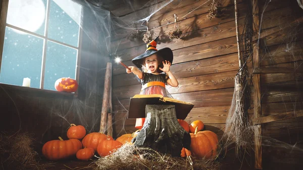 Halloween. child little witch with magic wand and reading a mag