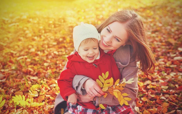 Happy family: mother and child little daughter play cuddling on autumn