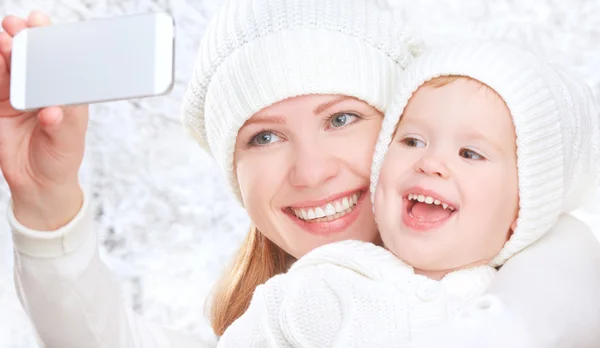 Selfie  in winter. happy family mother with daughter and photographed self on  mobile phone