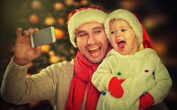 Selfie  in Christmas. happy family dad playing with daughter and photographed on  mobile phone