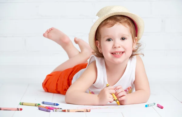 Happy little artist  girl in a hat draws pencil